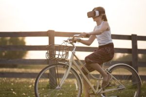 Girl riding a bicycle with a pair of VR glasses - nothing is impossible any longer in terms of software investment trends.