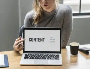 a girl pointing to the word content on the screen of her laptop