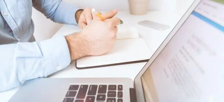 Image of person taking notes next to laptop.