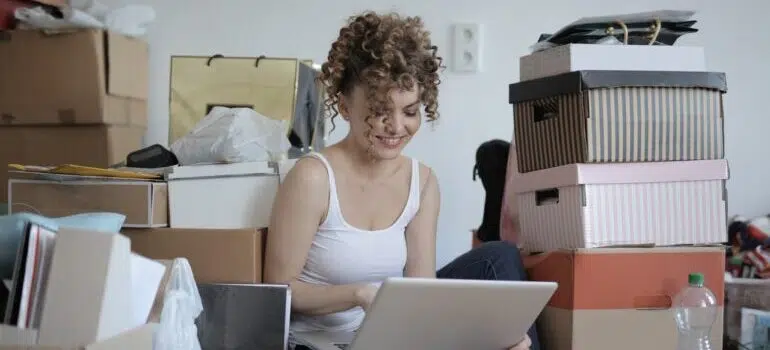 Woman surrounded by boxes, looking at her laptop