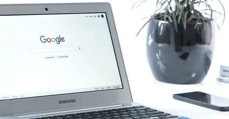 A laptop on a desk, displaying Google's search engine page.