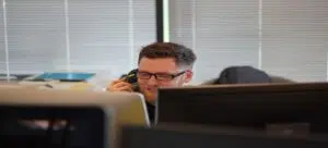 A man talking on a phone in an office.