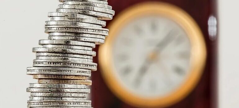 Stacked coins in front of a clock.