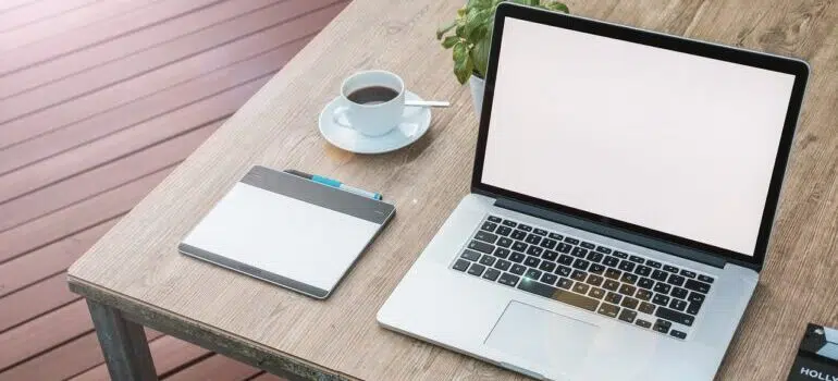 a white-screen laptop on a desk next to a cup of coffee