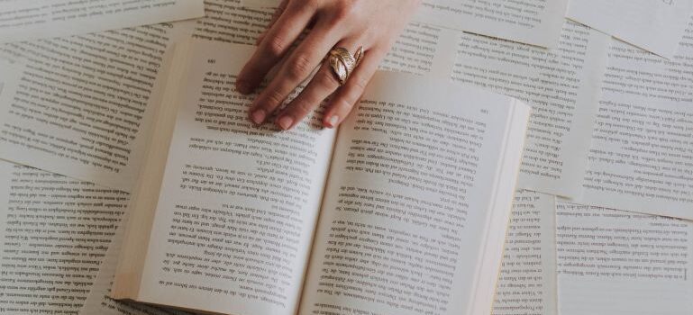 Dozens of open books, with a coffee mug.