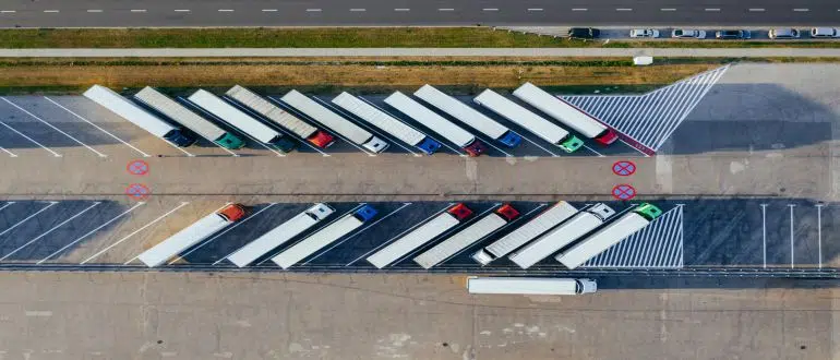 Drone shot of moving trucks on a parking lot.