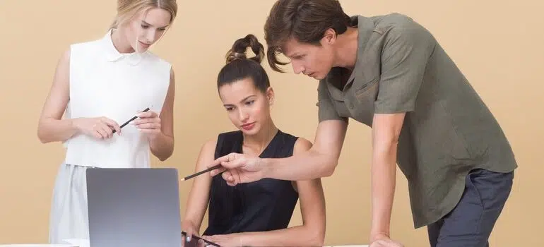 Three people looking at a laptop.