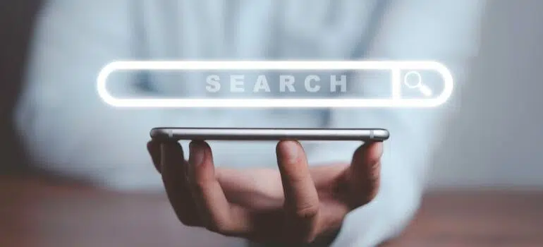 Person holding a smart phone, with search engine bar illustration above it.