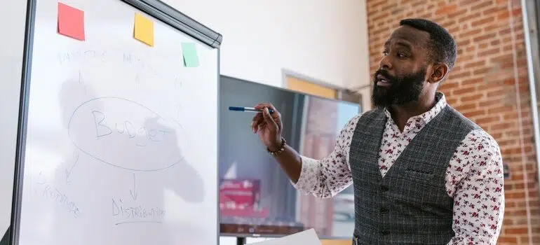 Man using a white board to explain something in a meeting.