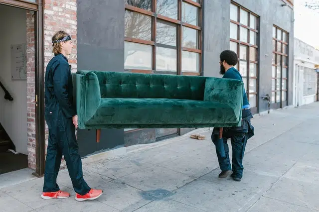 Two movers carrying a green couch