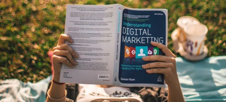 Person holding a book on understanding digital marketing.