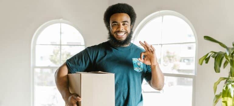 Moving crew member holding a box and smiling.