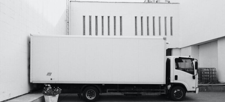 A white truck parked in front of a white building.