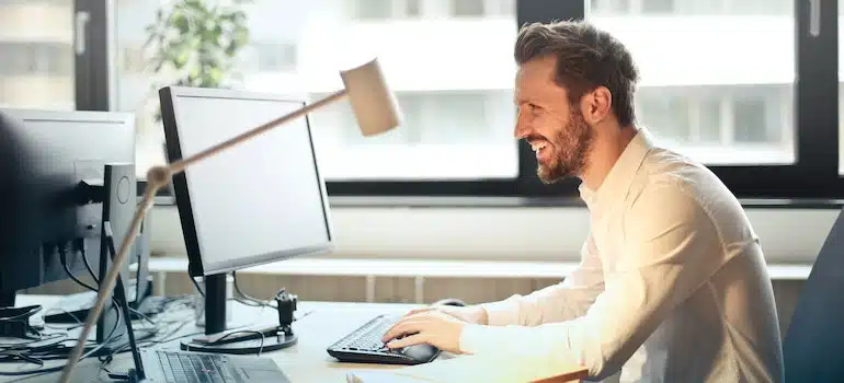 A man looking at a computer screen, laughing and reading about types of email campaigns movers can consider