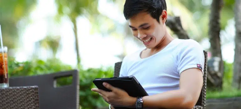 A man happily reading on a tablet, illustrating the power of engaging content for backlinks for moving companies in big cities.