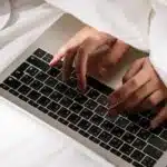a close-up of hands typing on a laptop in bed, checking newsletter ideas with seasonal moving tips