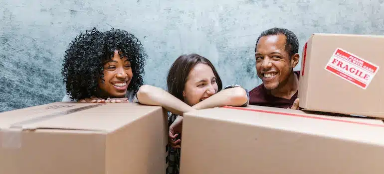Three people smiling and holding boxes