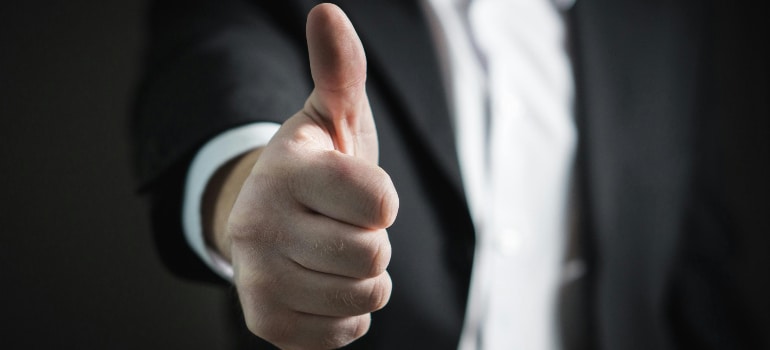A person in a suit showing a thumbs up. 