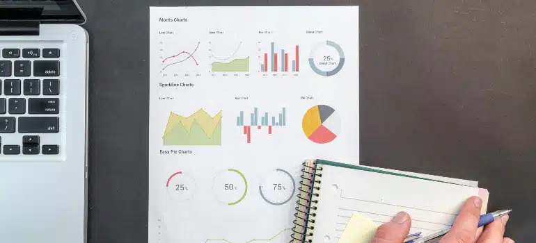 Workspace showing statistical charts and a person taking notes, demonstrating market research analysis essential to understanding why localized digital ads work.